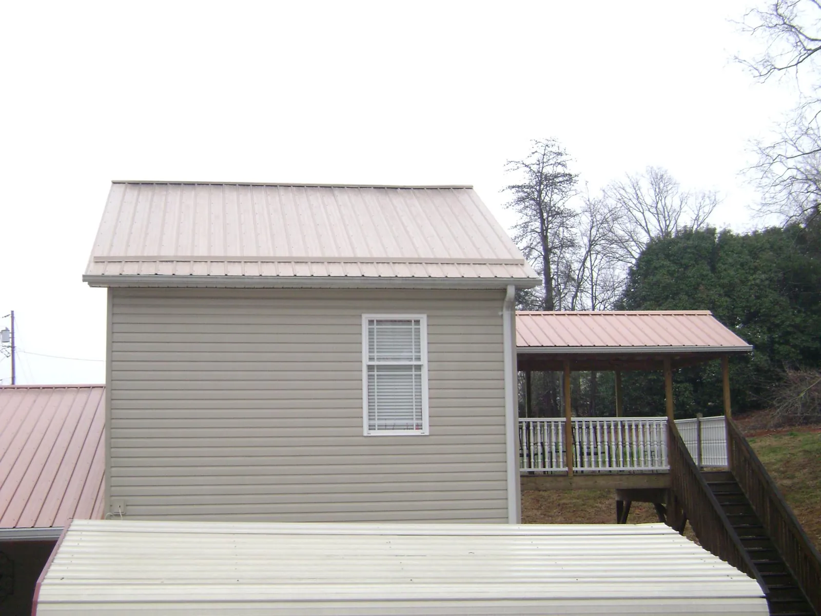 Tan metal roofs on a two story addition and attached porch, from a Roof Replacement job in Dublin